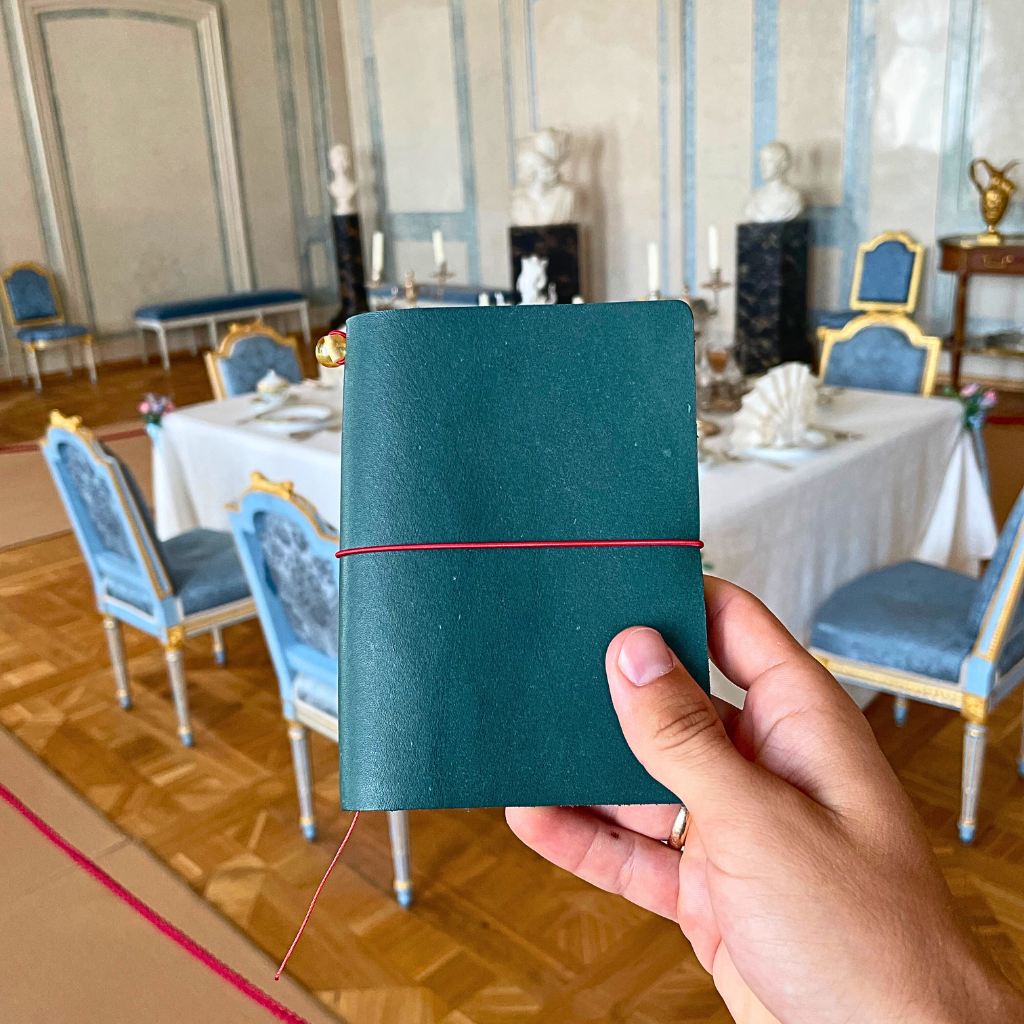 bielinis-petrol-blue-vellum-leather-notebook-held-in-vintage-luxury-dining-room.png