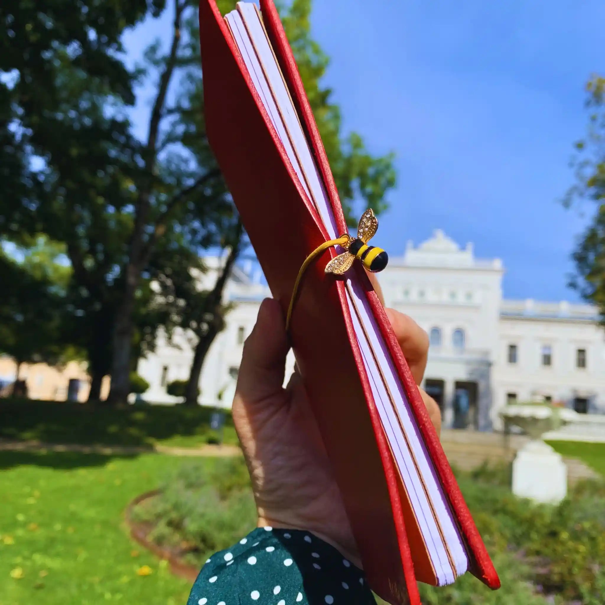 bielinis-red-leather-journal-bee-pendant-yellow-black-in-hand.webp