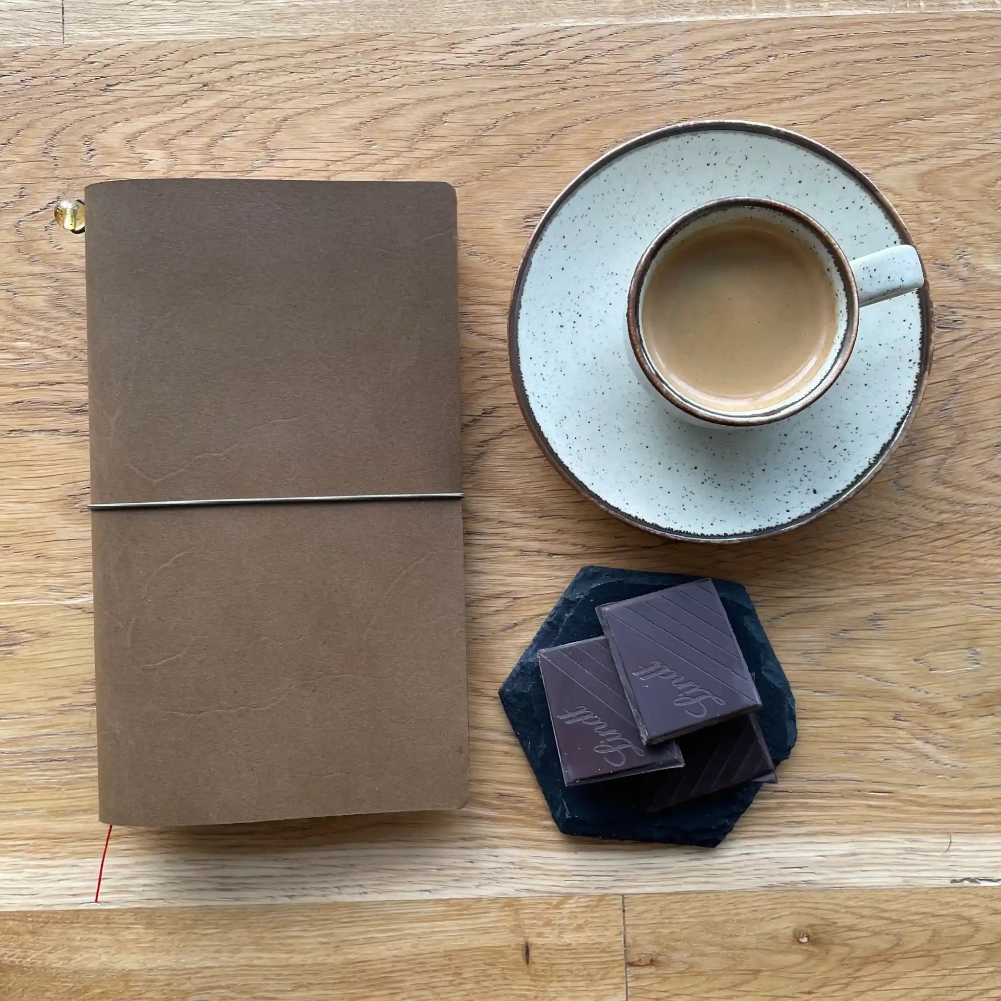 Bielinis handmade traveler’s journal in rich army green leather, Atlas size, flat lay on wooden table with coffee showcasing premium craftsmanship and pause the time.