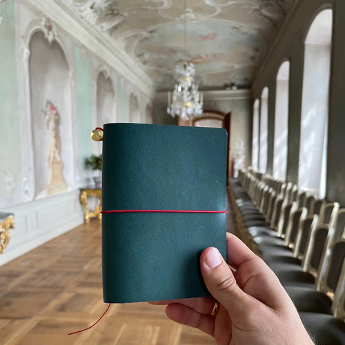 Handmade petrol blue leather traveler's journal held in front of Rundāle Palace, Vellum size