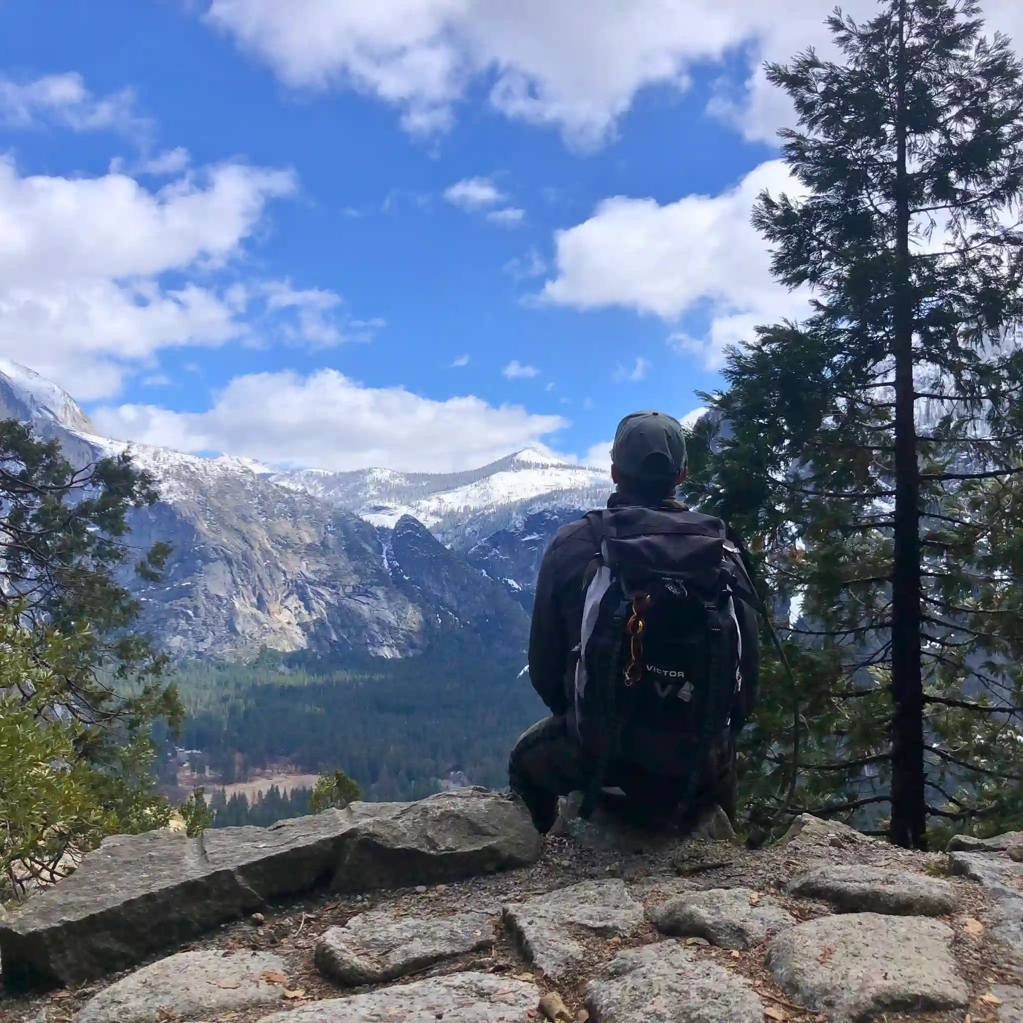 Person siting on the edge of a mountain in Yosemite, capturing a moment of inspiration—perfect companion for a handmade leather traveler’s journal by Bielinis.